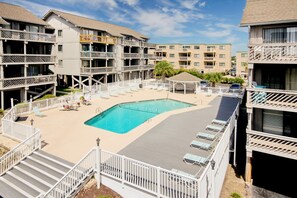 A hotel with a swimming pool surrounded by balconies and lounge chairs.