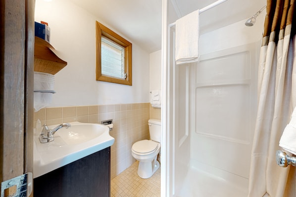 Un baño con lavamanos, inodoro y cortina de ducha.