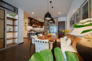Enjoy a stylish living space with a central dining area, sofa, and kitchen.