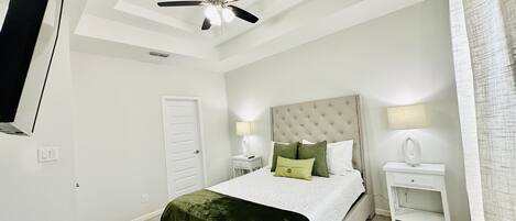 A bedroom with a bed, a ceiling fan, a nightstand, and a bedside lamp.