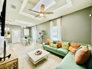 Ein modernes Wohnzimmer mit einem grünen Sofa, einem Couchtisch und einem Deckenventilator.