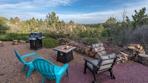 Une terrasse extérieure équipée d’un barbecue, d’un foyer et d’un espace salon.