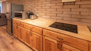Une cuisine moderne dotée de meubles en bois, d’un réfrigérateur en acier inoxydable, d’un four à micro-ondes encastré, d’un grille-pain et d’une cuisinière à gaz.