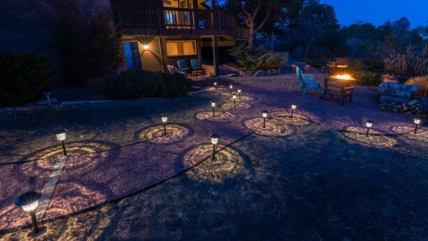 Un espace patio avec des sièges d’extérieur et un foyer, le tout agrémenté d’un éclairage décoratif.