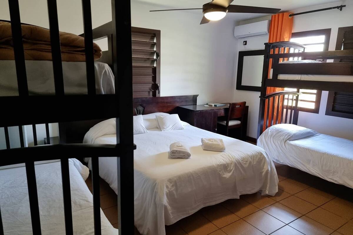 Una habitación con literas, un escritorio, una silla y un ventilador de techo.