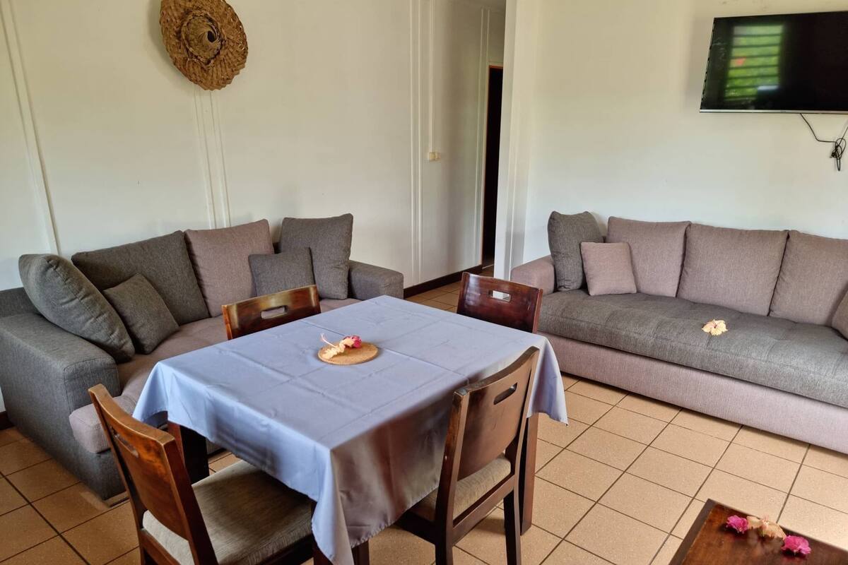 Una sala de estar con una mesa de comedor, dos sofás y un televisor.