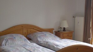A bedroom with two single beds, a bedside table with a lamp, and a radiator. - Vacation apartment 1, 68 sqm for 1-2 persons (Berchtesgaden)