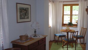 A dining area with a table, chairs, a lamp, a basket, and a framed picture on the wall. - Vacation apartment 1, 68 sqm for 1-2 persons (Berchtesgaden)