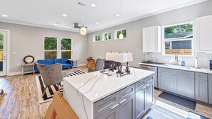 Une cuisine moderne avec un îlot central, des meubles de couleur grise et un canapé bleu dans l’espace salon.