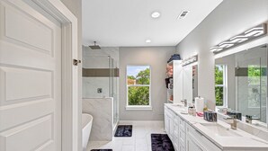 Une salle de bain moderne avec un grand miroir, des meubles blancs, une baignoire et une douche.