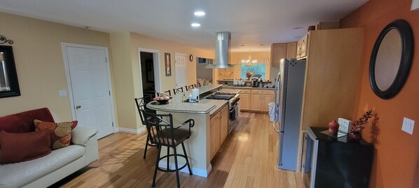 A modern kitchen with a central island, wooden cabinets, and a refrigerator.