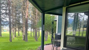 A covered outdoor deck with a view of a grassy area and trees. - Charming condo on the golf course. 15 min from McCall. (New Meadows)