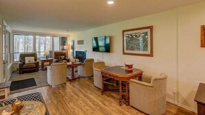 A spacious living room with a fireplace, comfortable seating, a flat-screen TV, and large windows. - Charming condo on the golf course. 15 min from McCall. (New Meadows)