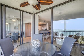 Relax in this open-plan living space with a glass-enclosed balcony, featuring a central table, comfortable seating, and a kitchen area.