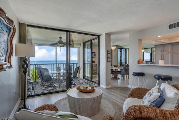 Relax in this stylish living room with ocean views through large glass doors, featuring a sofa, coffee table, and floor lamp.