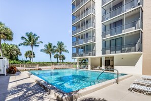 Relax by the rectangular pool surrounded by lounge chairs and umbrellas.