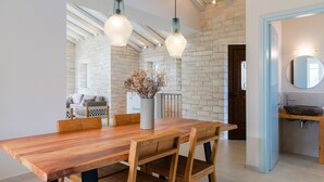 A dining area with a wooden table and chairs, a vase with dried flowers, and a brick wall. - Villa Jacaranda - Vacation villa with private and heated pool by Agni Bay, Corfu (Agní)