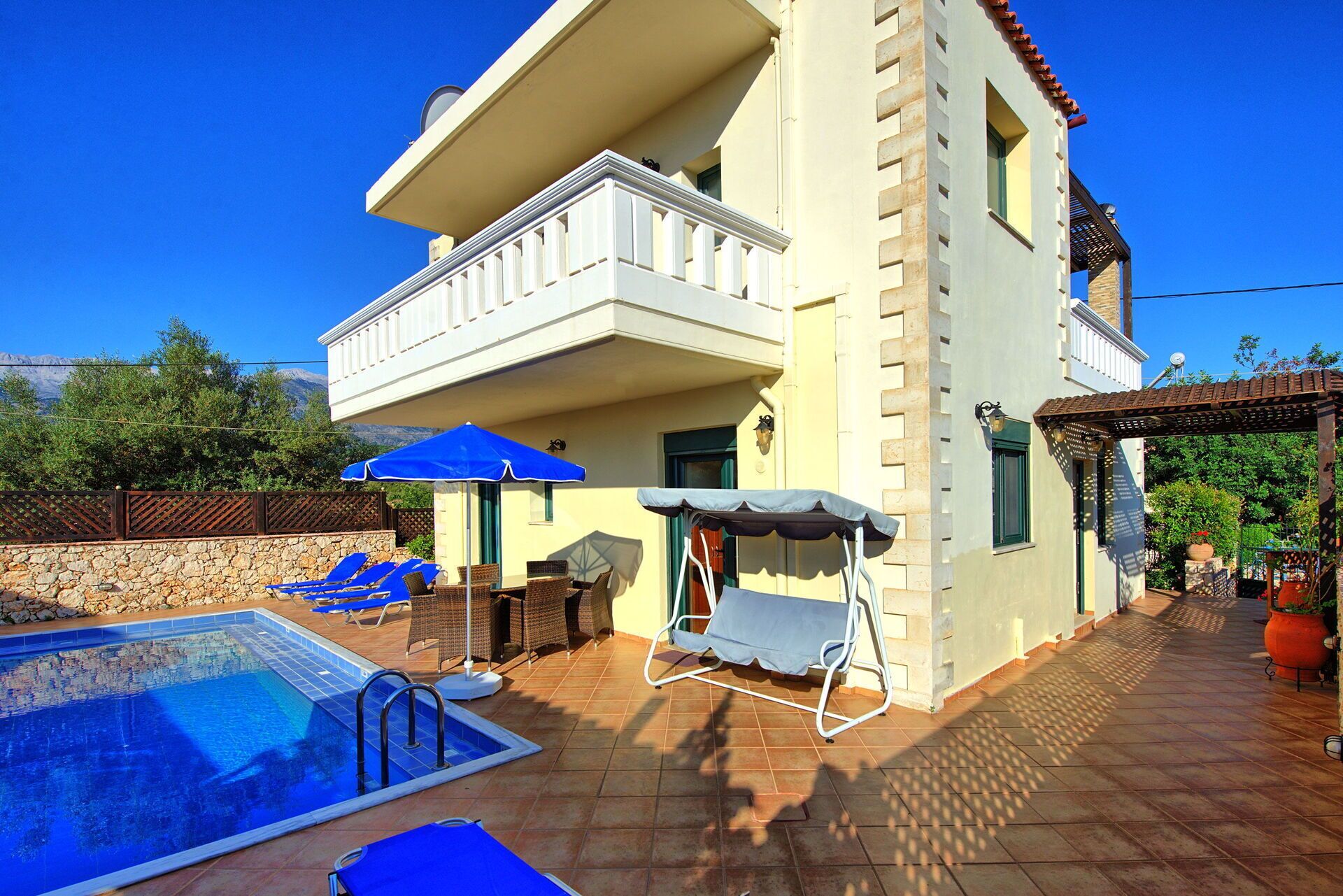 A two-story building with a swimming pool, outdoor seating, and a pergola.