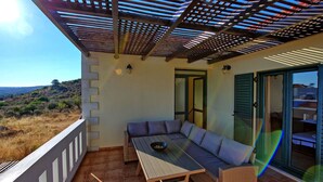 Un balcone con divano, tavolino e vista sulla campagna.