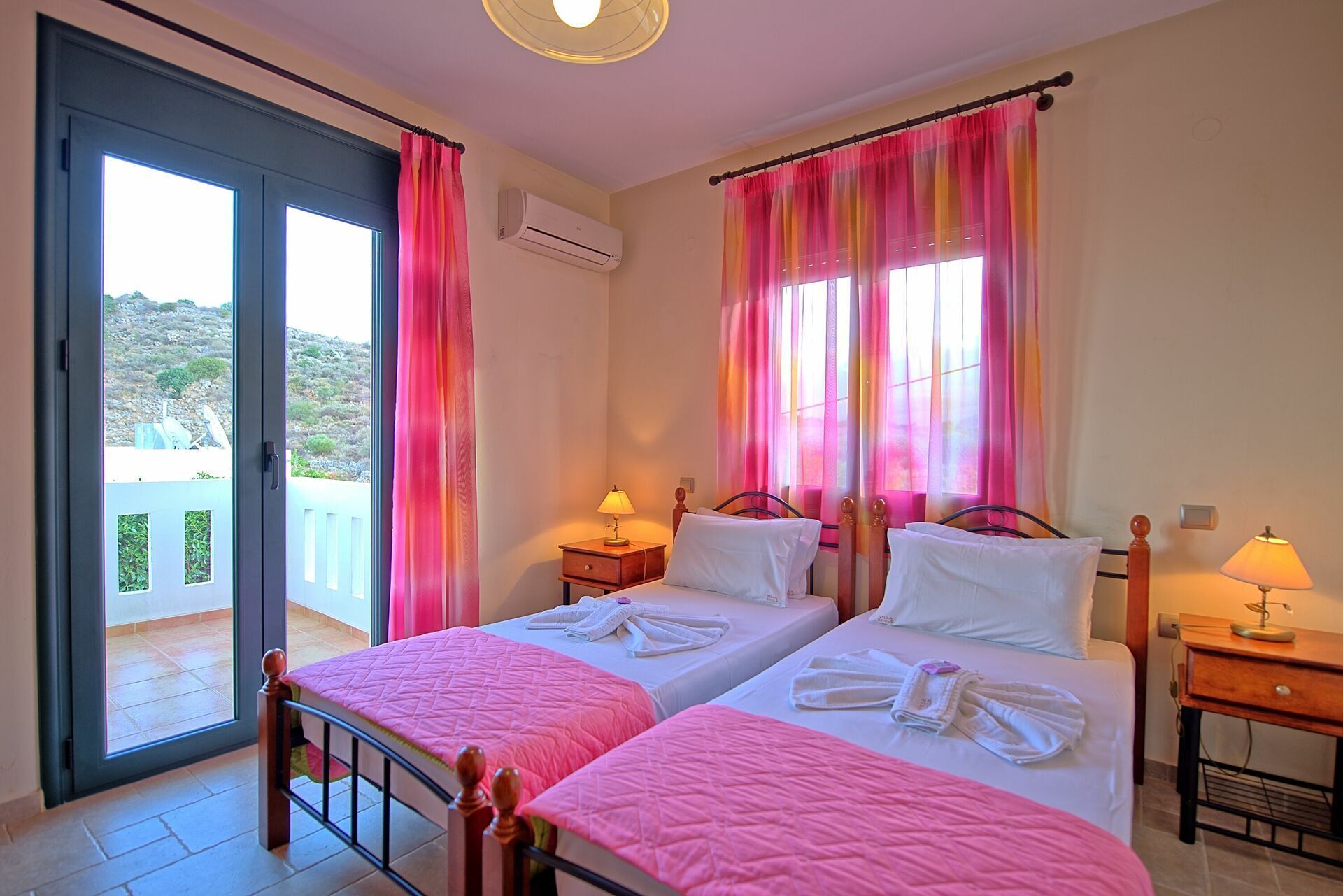 A hotel room with two beds, a balcony, and a view of the landscape.