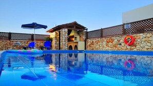 Una piscina con una parete in pietra, un'area barbecue e un segnale che indica divieto di parcheggio.