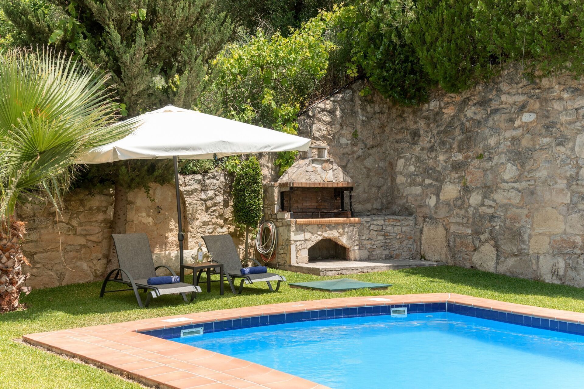Una piscina con parete in pietra e forno in mattoni.