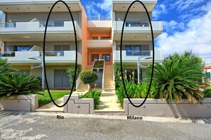 A modern two-story building with balconies, a central entrance, and a small garden area. - Cabanavillas Rio - Holiday Villa rental with pool in Agia Marina, Crete (Agia Marina)
