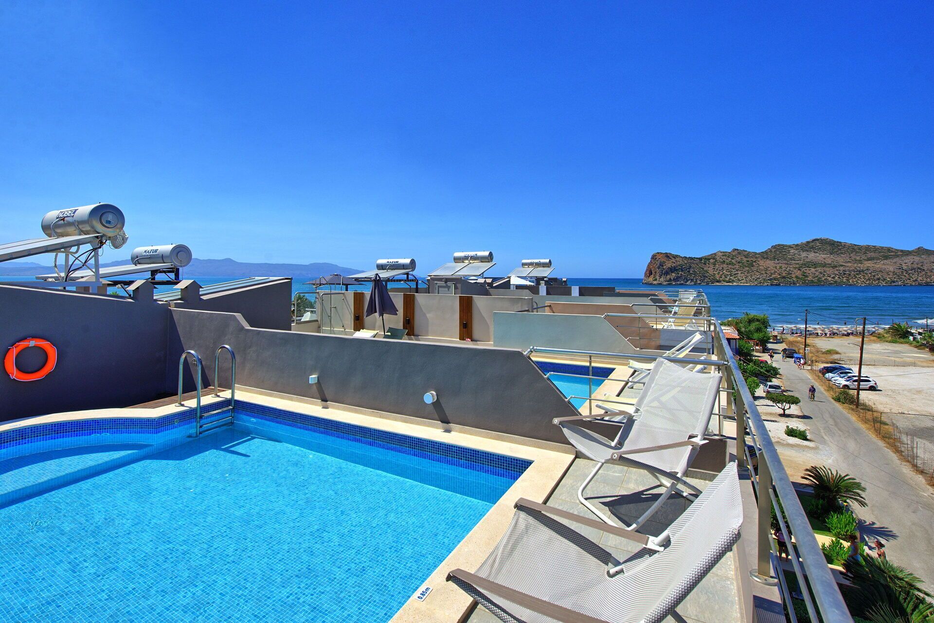A rooftop pool with a clear view of the sea and mountains.