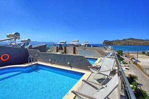 A rooftop pool with a clear view of the sea and mountains.