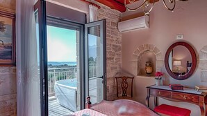 Habitación de hotel con una cama, tocador con espejo, una mesita y vista al exterior.