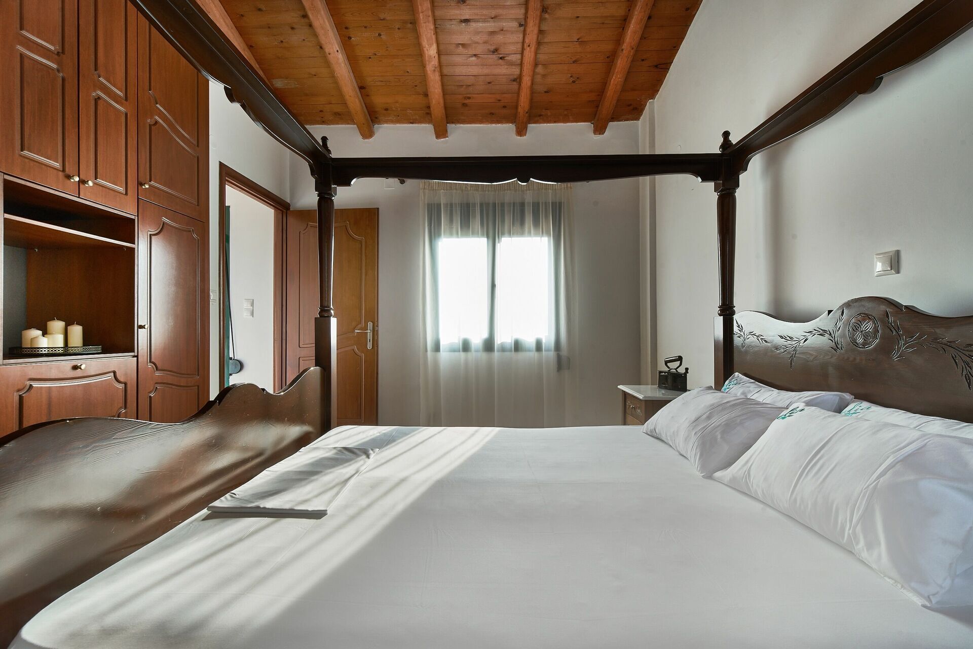 Un lit à baldaquin avec une tête de lit en bois, une armoire en bois et une table de chevet avec une lampe.