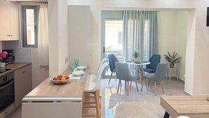 A modern kitchen with a dining area, a coffee machine, and a fruit bowl on the counter.