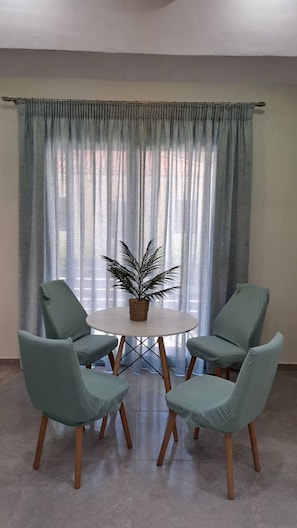 A dining area with a round table, four chairs, and a potted plant.