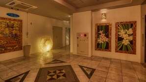 A hotel lobby with a tiled floor, directional signs, a phone, and decorative paintings. - HOTEL PACIFIC VIEW (Okinawa)