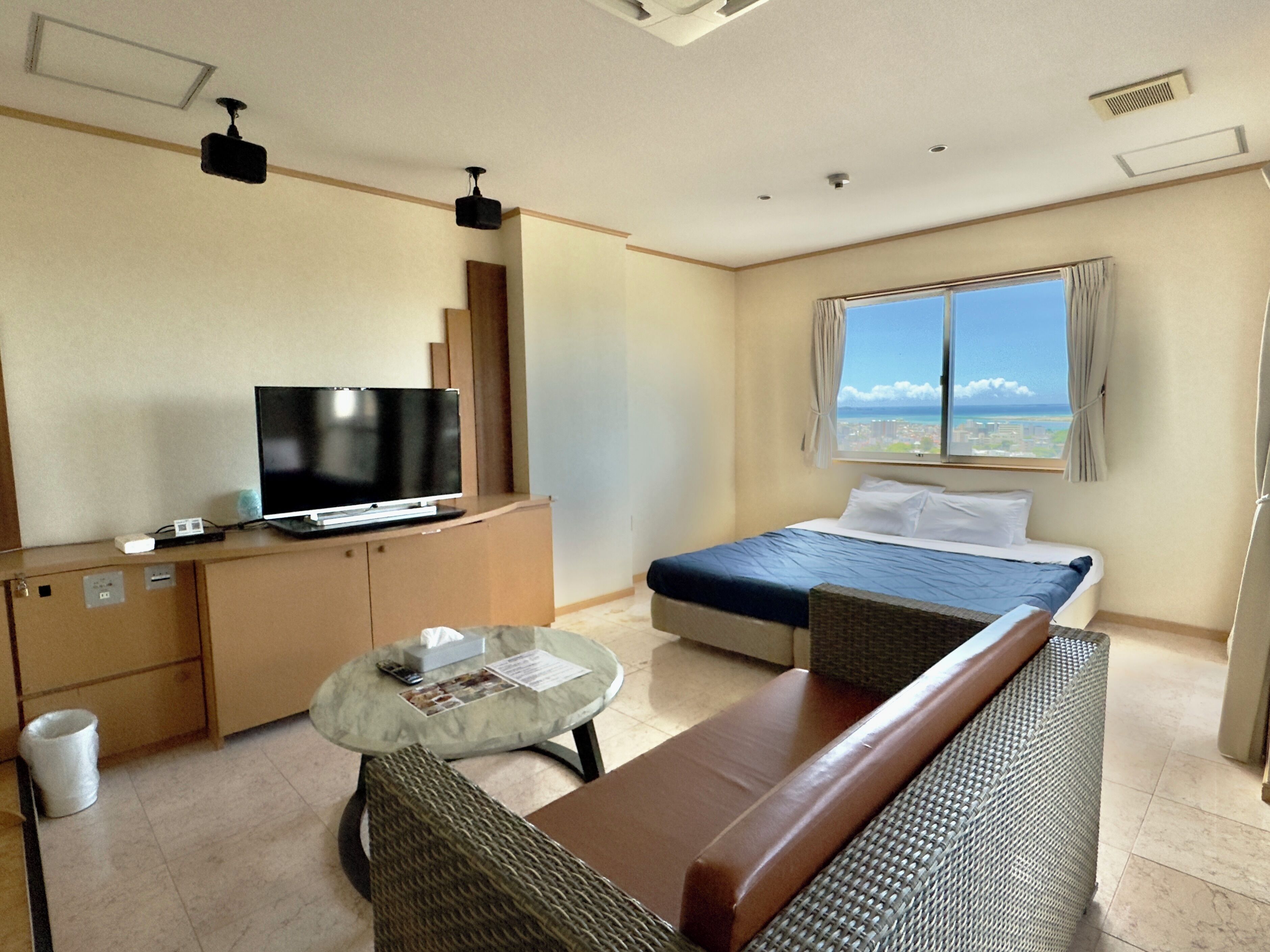 A hotel room with a bed, a television, a small table, and a sofa.