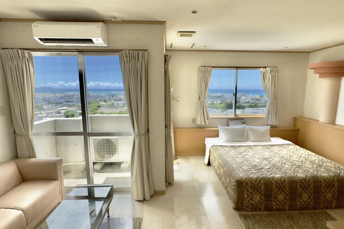 Une chambre d’hôtel comprenant un lit, un canapé, une petite table et un balcon équipé d’un appareil de climatisation.