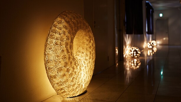 A hallway with a large, ornate, illuminated sculpture on the left. - HOTEL PACIFIC VIEW (Okinawa)