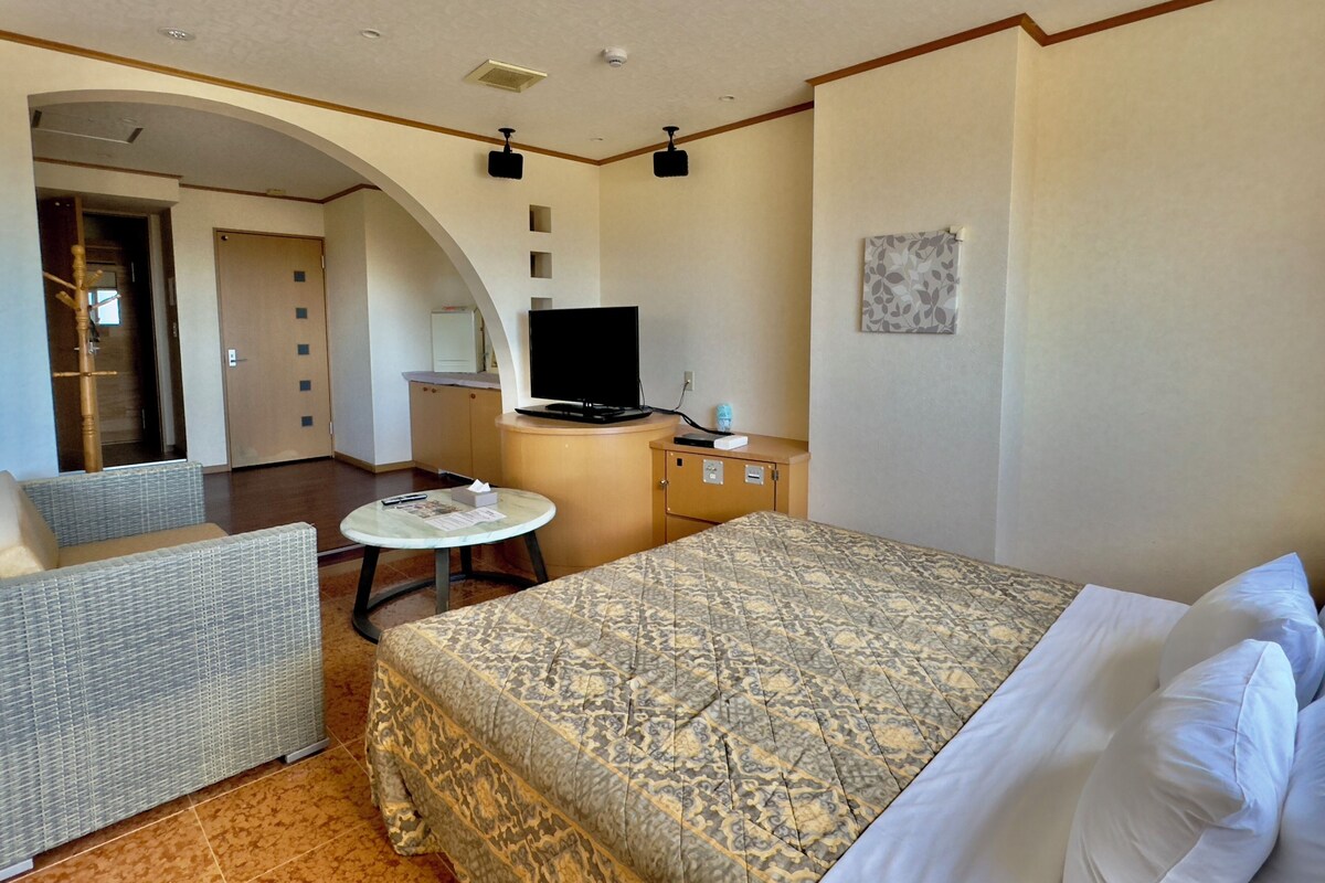 A hotel room with a bed, a television, a desk, and a chair.