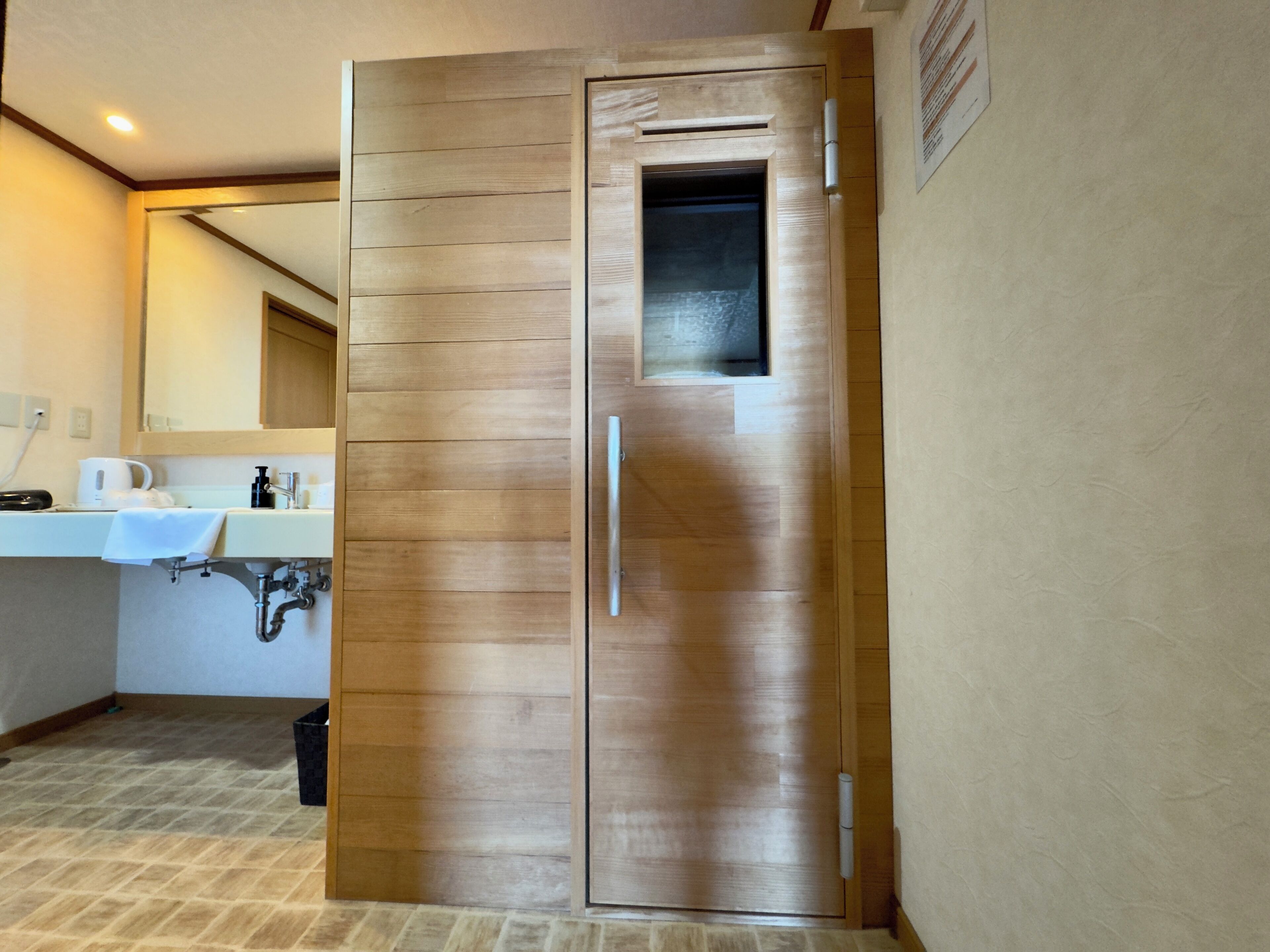 A bathroom with a wooden door, a sink, and a mirror.