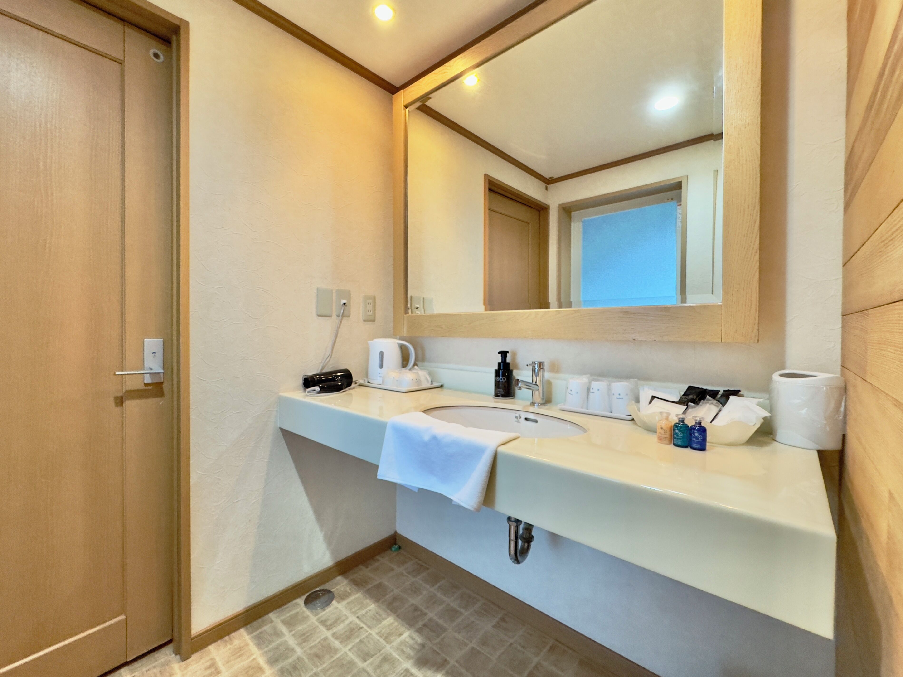 A bathroom with a sink, mirror, towel, and toiletries.