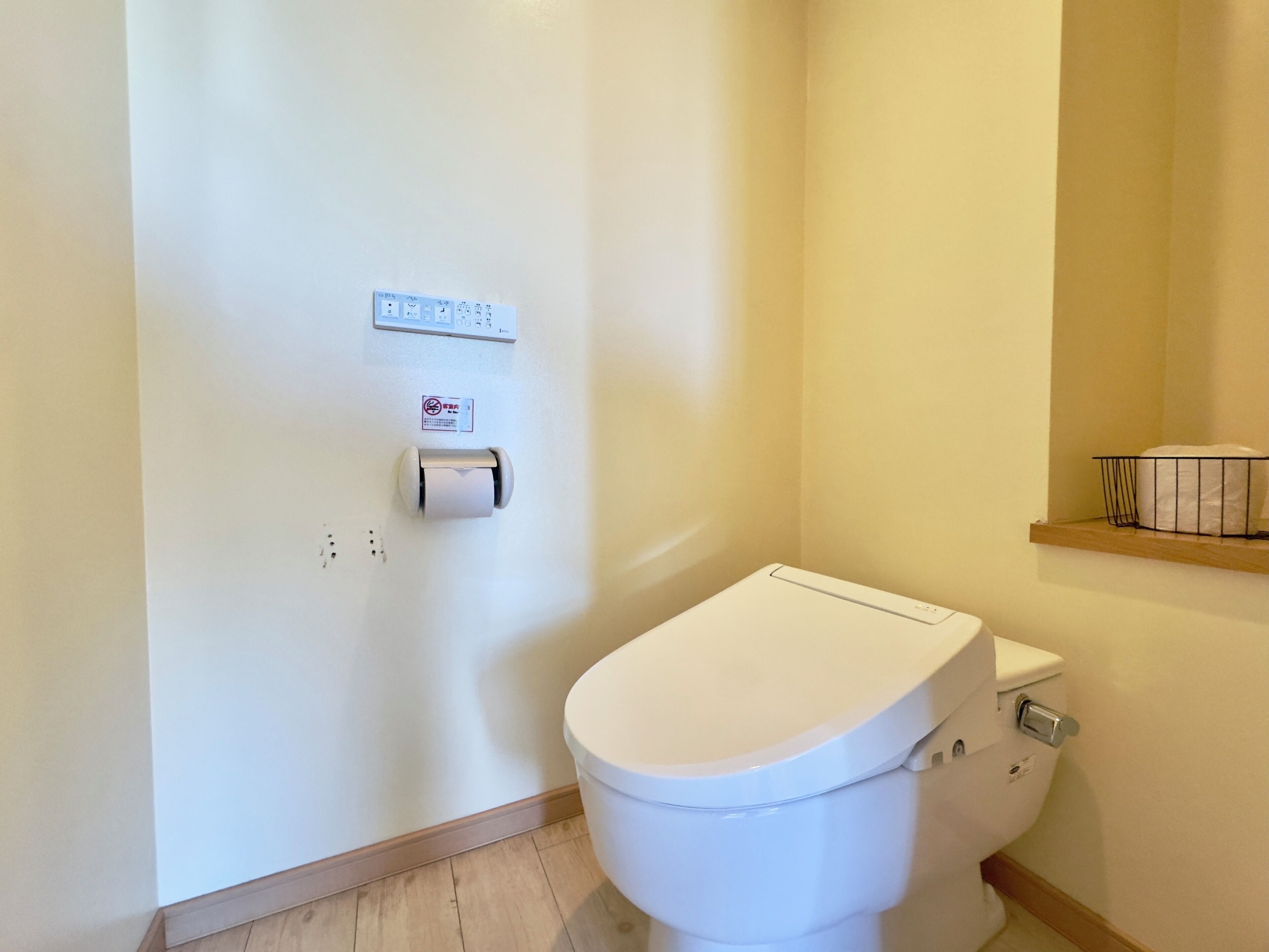 Eine weiße Toilette mit Papierhandtuchspender und einer kleinen Ablage darüber.