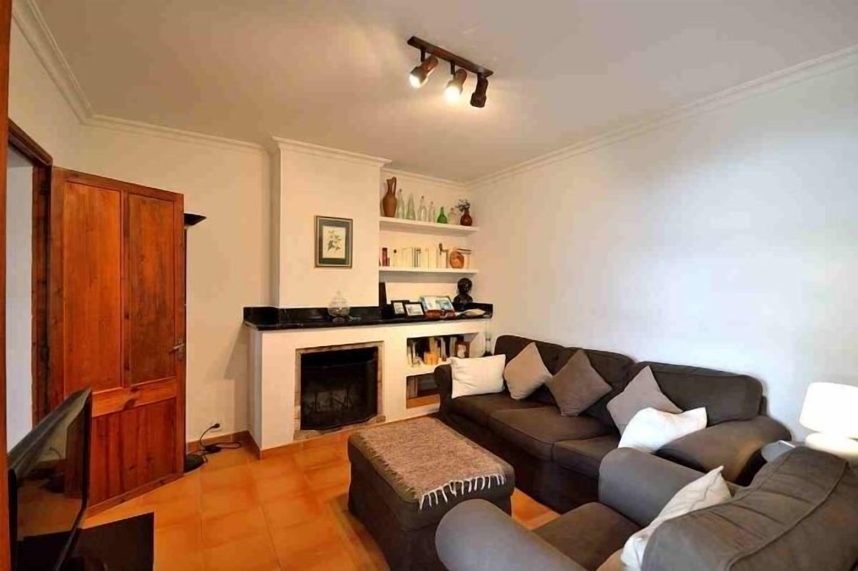 A living room with a fireplace, a sofa, a television, and a wooden door.