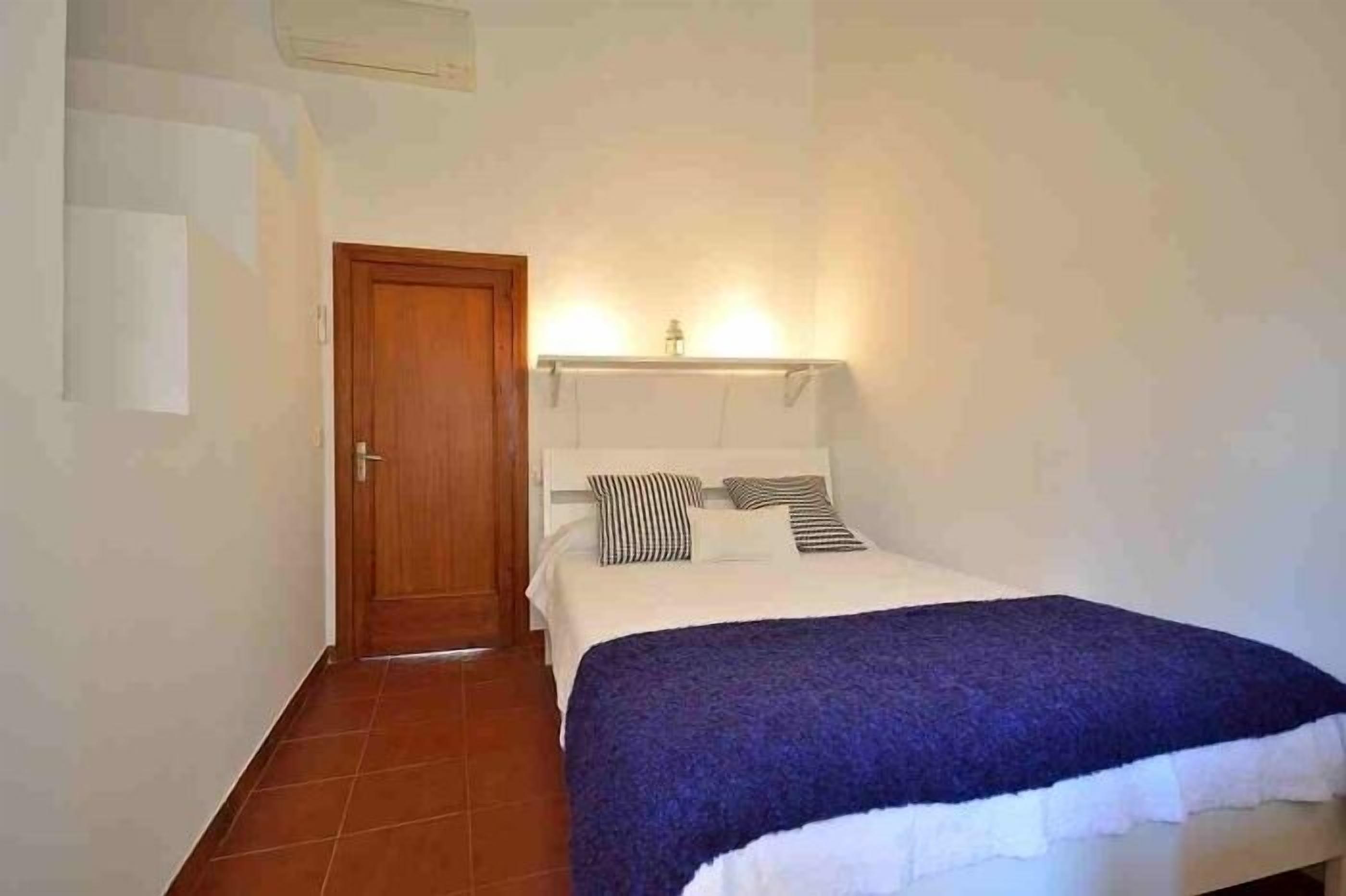 Ein Schlafzimmer mit einem Bett, einer Holztür und einer Wandleuchte.