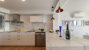 A modern kitchen with marble countertops, stainless steel appliances, and pendant lighting. - Apartment Faroles 1 By SunVillas Mallorca (Puerto Pollença)