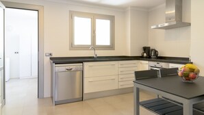 A modern kitchen with a dishwasher, a coffee maker, and a fruit bowl on the counter. - Apartment Cormes By SunVillas Mallorca (Puerto Pollença)
