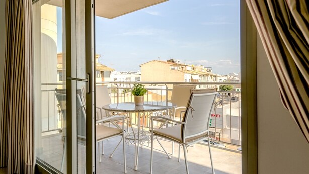 A balcony with a round table, two chairs, and a potted plant. - Apartment Cormes By SunVillas Mallorca (Puerto Pollença)