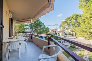 Enjoy casual dining and socializing on this balcony with a table and chairs, overlooking a scenic street view.