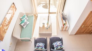 A sunlit room with a sofa, two armchairs, a small table, and a window with curtains. - Apartment Voltor 2 E By SunVillas Mallorca (Puerto Pollença)