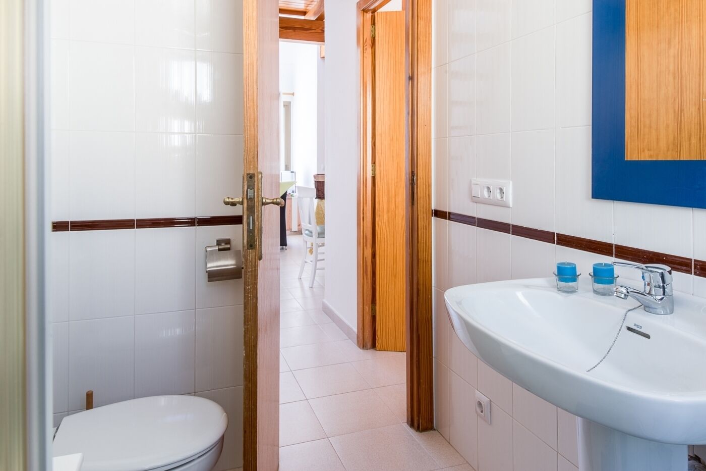 A bathroom with a white sink, a toilet, and a wooden door.