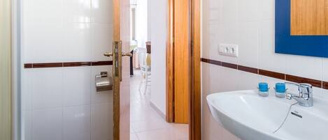 A bathroom with a white sink, a toilet, and a wooden door.